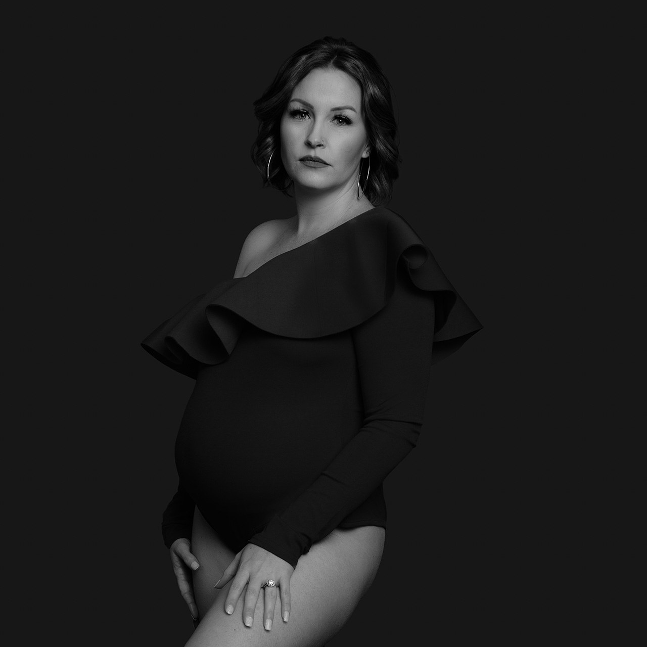 black and white maternity photo of a woman in a black bodysuit.